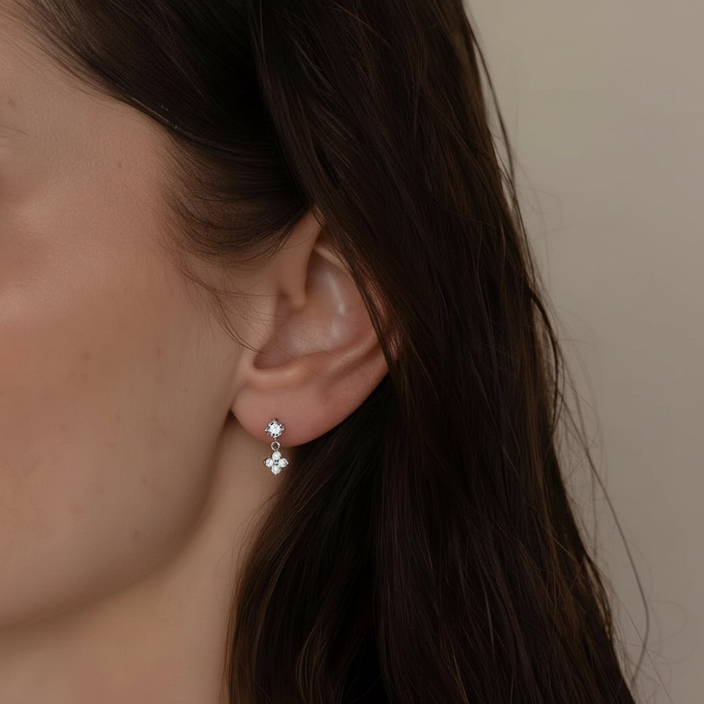 Close-up of an ear wearing a delicate earring with a neutral background