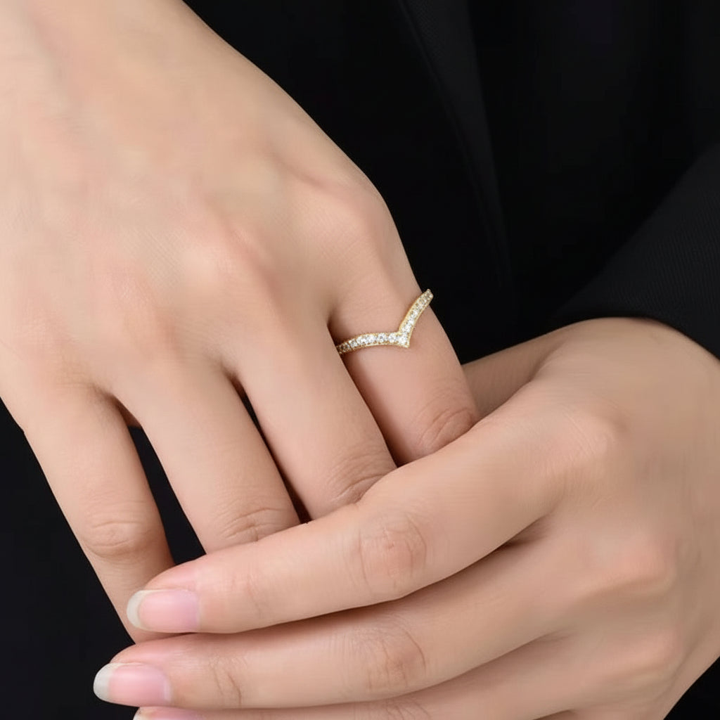 Close-up of a hand wearing a gold ring with a black background