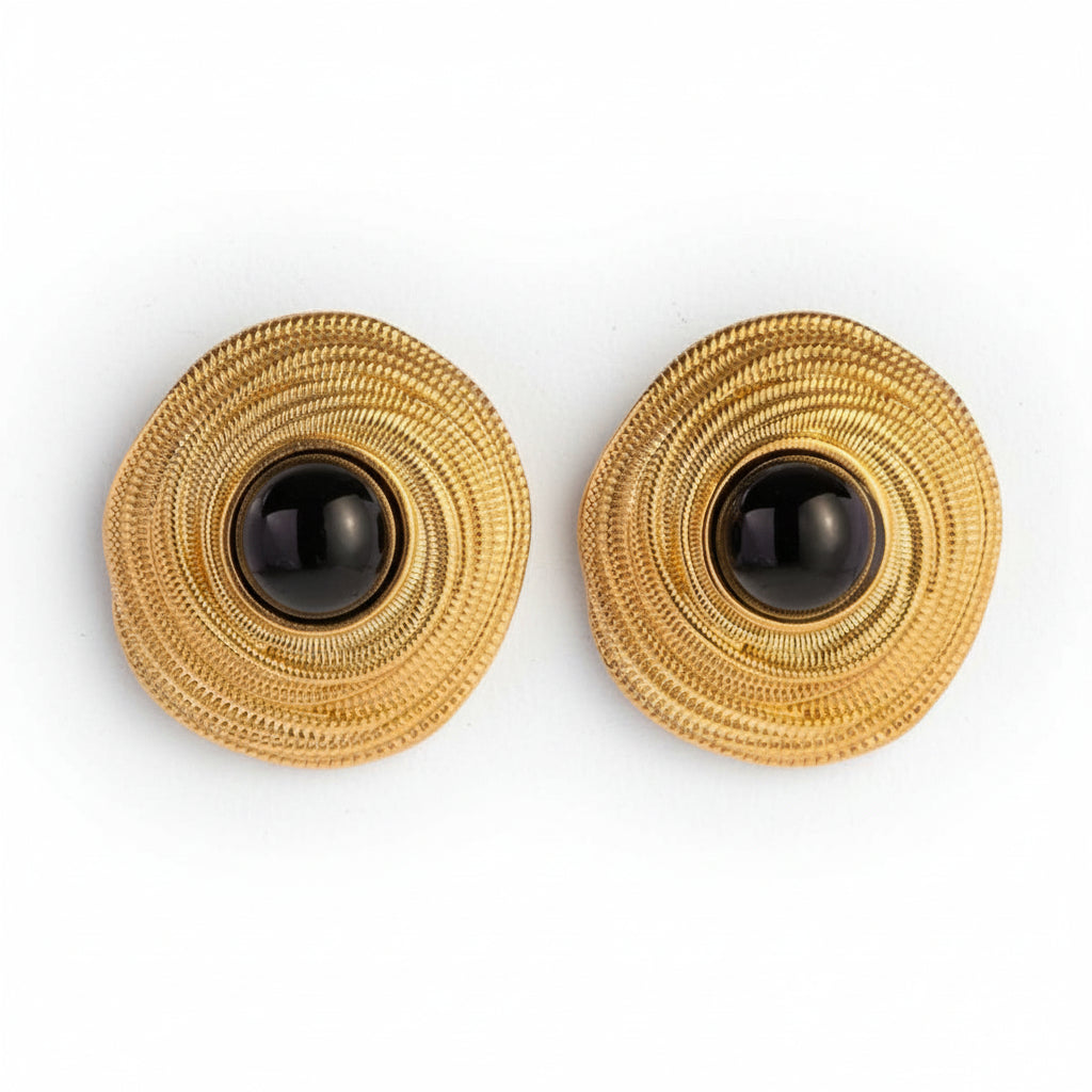 A pair of gold-plated earrings with black agate stones in the center, featuring a textured circular design.
