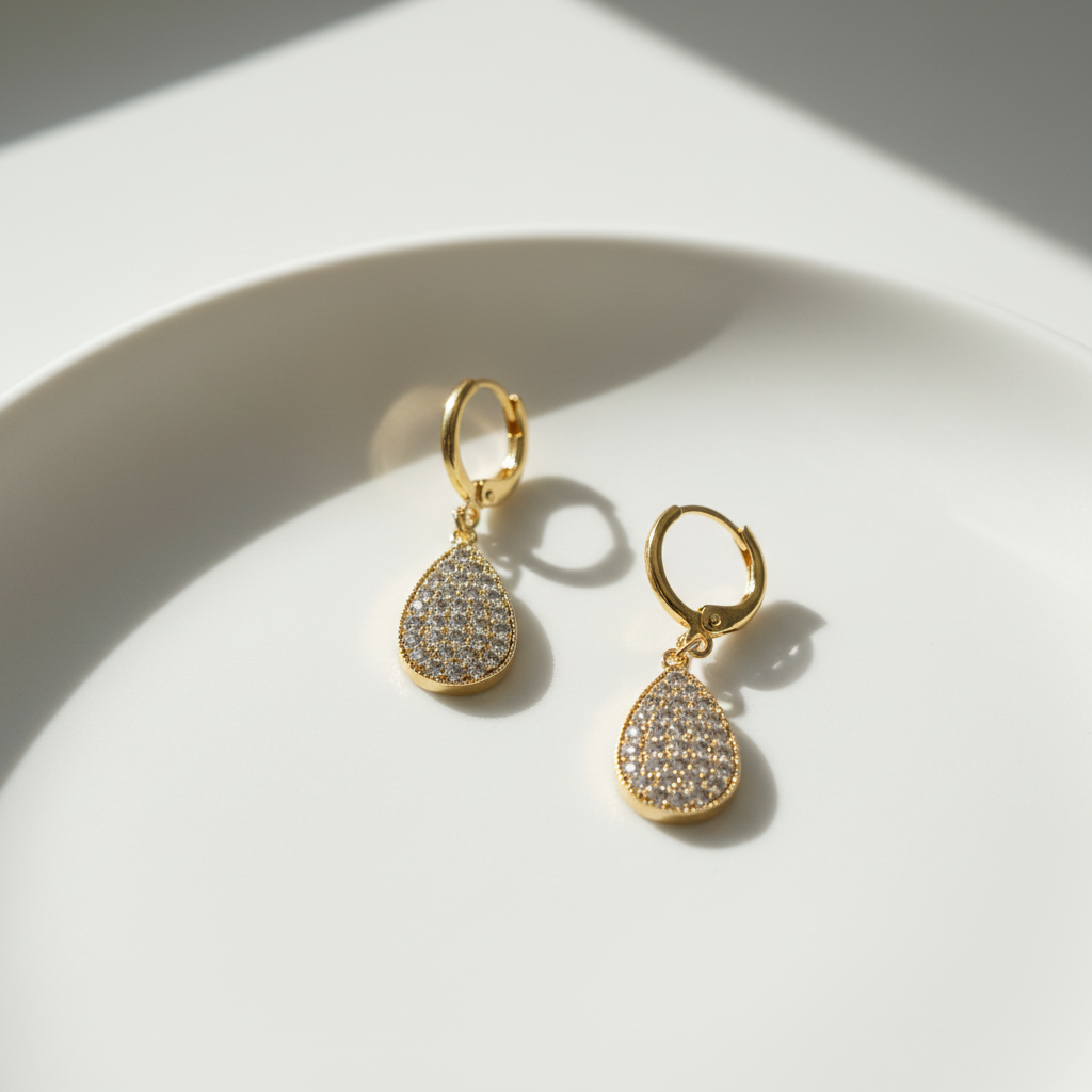 A pair of gold-colored earrings with a waterdrop design, with zircon crystals.