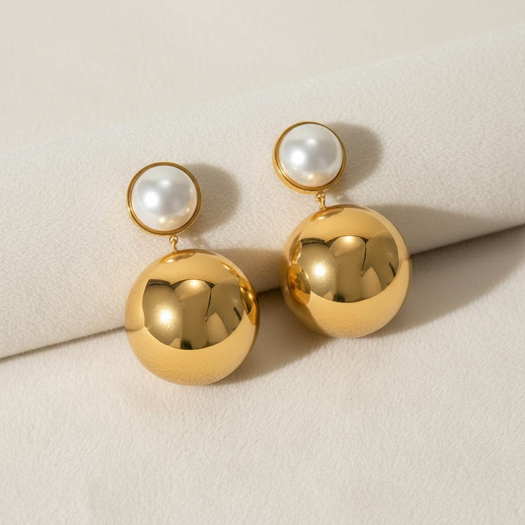 A pair of gold-plated drop earrings with a spherical design and a smaller circular detail at the top.